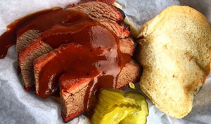 sliced brisket with bread, sauce, and pickles