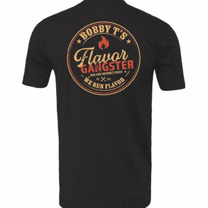 A black short-sleeve t-shirt shown from the back, featuring a large circular graphic print with the text 'BOBBY T'S Flavor GANGSTER' and 'WE RUN FLAVOR' in tan, orange, and red tones.